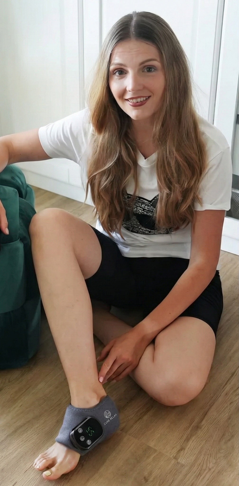 Une femme assise au sol dans un intérieur clair, l'appareil porté au pied